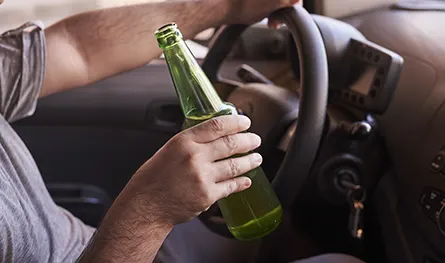 Botella de cerveza en manos de un hombre conduciendo Botella de cerveza en manos de un hombre conduciendo